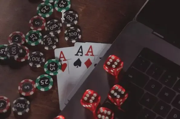 Fichas de colores, dos dados rojos y un par de ases apoyados sobre el teclado de un portátil.
