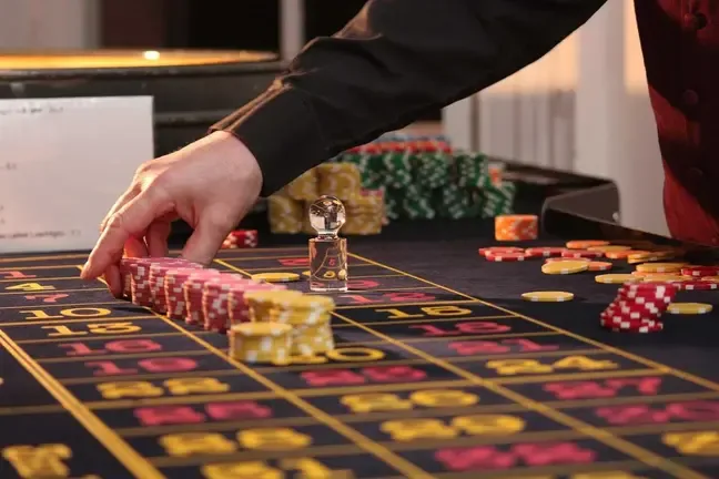 Manos colocando fichas sobre el paño numerado de una mesa de ruleta cualquiera.